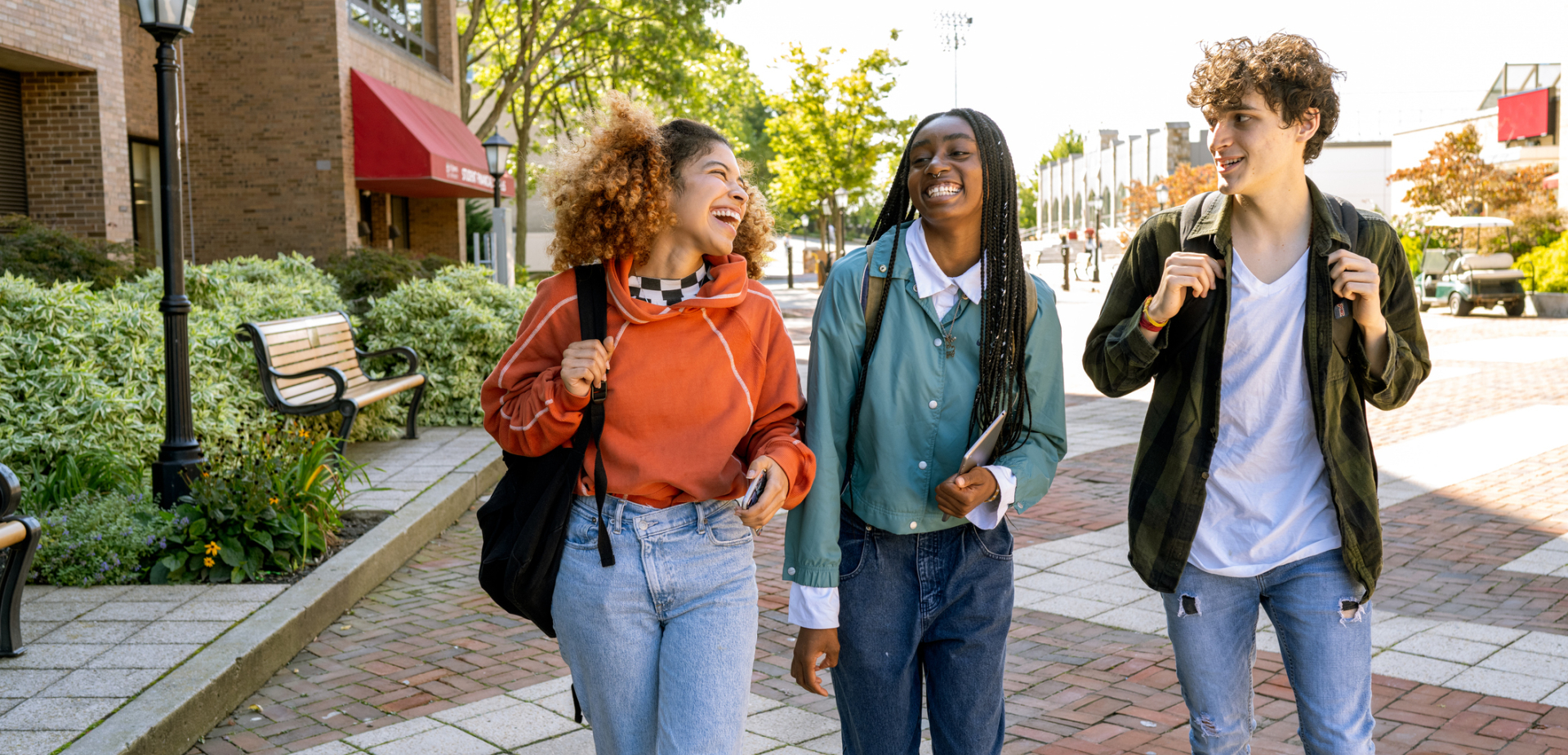 Diverse teens walking outside of school carrying their backpacks  