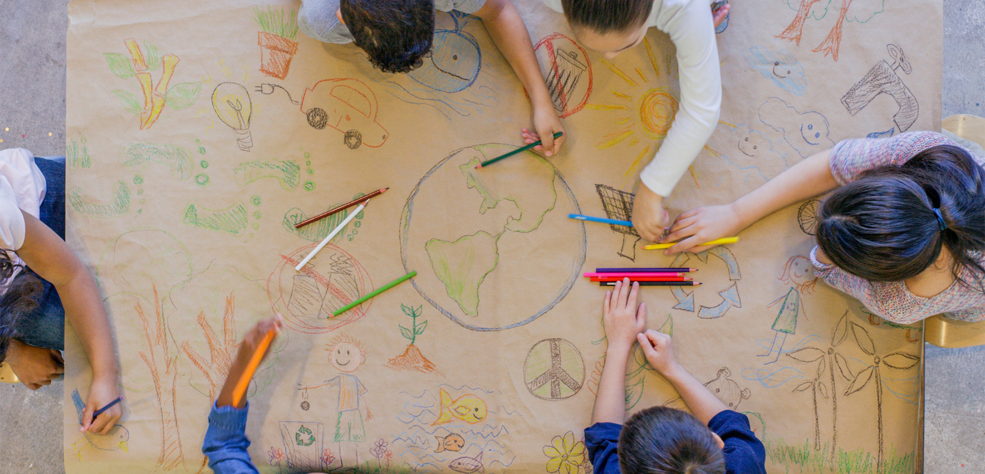 A bird's eye view shot of diverse elementary students around a table drawing on kraft paper