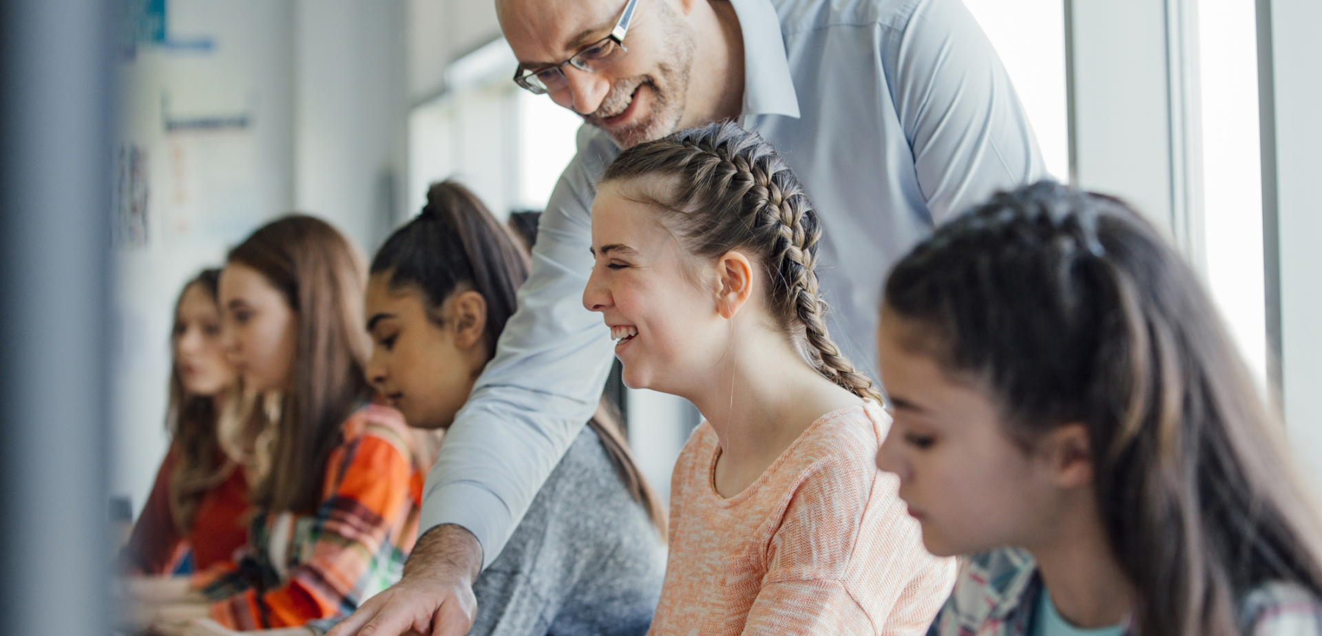 Teacher helping a student at her computer keyboard
